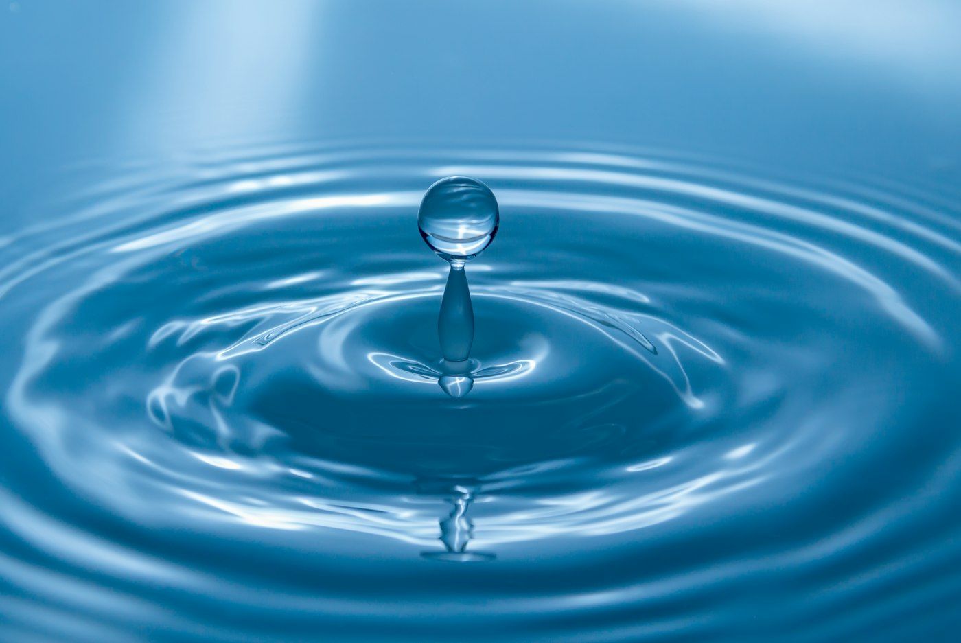Gota de agua cayendo sobre una superficie de agua azul